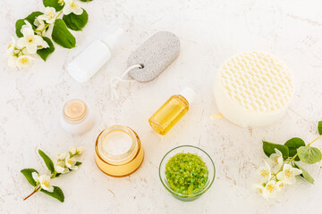 Body care products and branches of jasmine on the white background.
