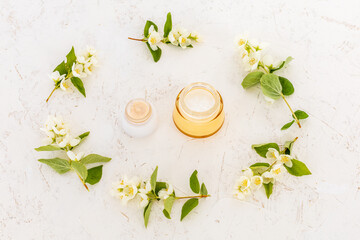 Body care products and branches of jasmine on the white background.