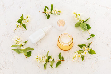 Body care products and branches of jasmine on the white background.