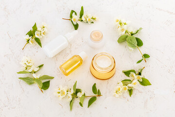 Body care products and branches of jasmine on the white background.