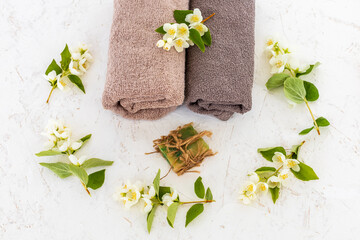 Towels with body care products and branches of jasmine on the white background.