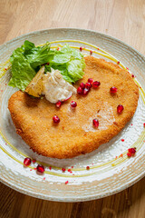 A beautifully plated crispy fillet with a garnish of lettuce, pomegranate seeds, and lemon