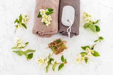 Towels with body care products and branches of jasmine on the white background.