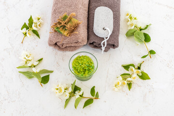 Towels with body care products and branches of jasmine on the white background.