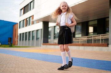 happy schoolgirl backpack ready for class. excited young student enjoying first day at modern...