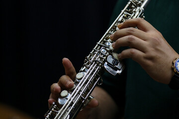 Close-Up of Musician Playing saxophone or flute in Studio with black solid background