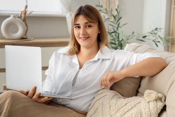 Obraz premium Young woman working remotely on laptop from home sofa, online education and business communication