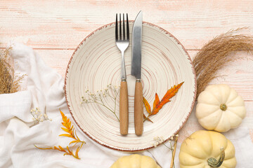 Beautiful table setting with fresh pumpkins, gypsophila flowers and autumn leaves on white wooden...