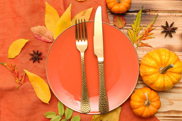 Beautiful table setting with fresh pumpkins, star anise and autumn leaves on wooden background