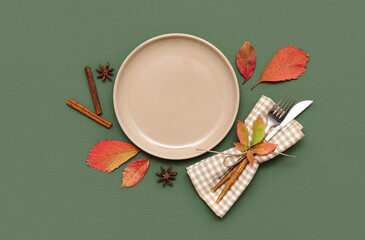 Beautiful table setting with star anise, cinnamon and autumn leaves on green background