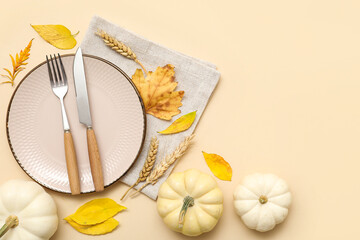 Beautiful table setting with fresh pumpkins, wheat and autumn leaves on beige background