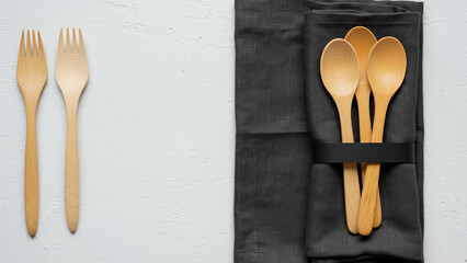 Eco-Friendly Wooden Spoons and Forks with Napkin on White Textured Background