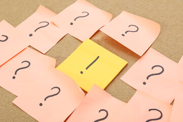 Sticky notes with question and exclamation marks on board, closeup