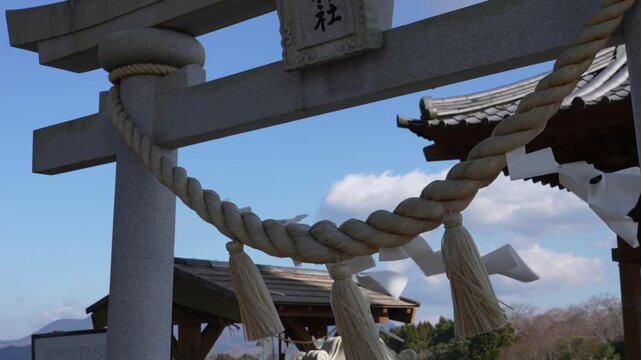 At the mountaintop, Tenman Shrine's stone torii stands&mdash;Shinto's iconic gate. Sacred shimenawa ropes and fluttering shide streamers dance in the wind.