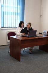 Two women meet to discuss a project and sign a contract.