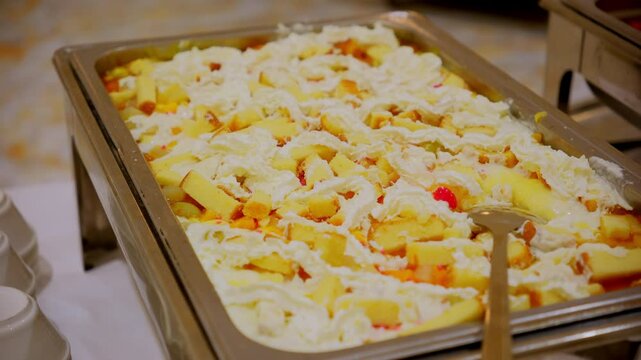 The tray contains fruit custard with chopped fruits and creamy sauce