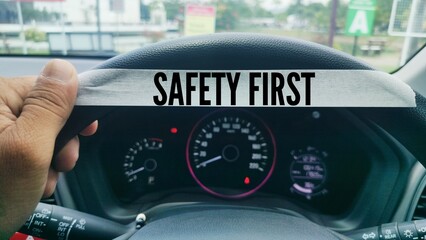 hands holding a car steering wheel and paper with the word SAFETY FIRST. the main concept of safety in driving