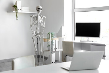 Fototapeta premium Interior of light hospital with human skeleton model and modern computer
