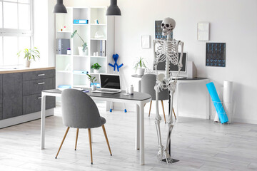 Interior of light hospital with human skeleton model, x-ray images, modern laptop and computer