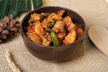 Sambal Goreng Hati Kentang or Hot Spicy Offal and Potatoes, Indonesian Traditional Cuisine, Typically Served During Eid Al-Fitr Celebration with Ketupat. Served on Brown Bowl, Wooden Background