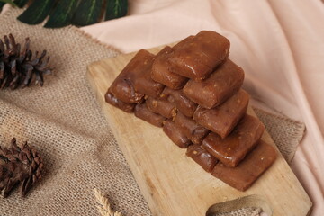 Stack of Jenang Ketan Dodol, Indonesian sweet snack made from glutinous rice flour, coconut milk, brown sugar and pandan leaves, set on rustic background