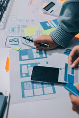 UX UI designer testing prototype on a phone, discussing and brainstorming on wireframes for a...