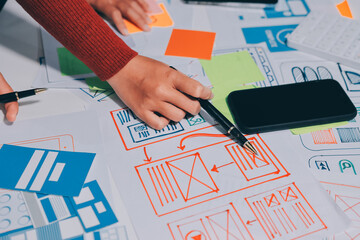 UX UI designer testing prototype on a phone, discussing and brainstorming on wireframes for a...