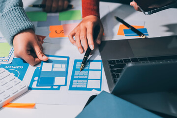 UX UI designer testing prototype on a phone, discussing and brainstorming on wireframes for a...
