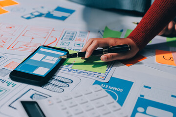 UX UI designer testing prototype on a phone, discussing and brainstorming on wireframes for a...