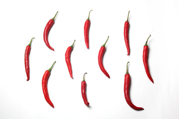 Individual bright red chili peppers are artfully scattered across a clean white background