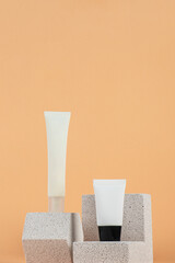 Plastic white tube for cream or lotion. Skin care or sunscreen cosmetic with stylish props on cream background.