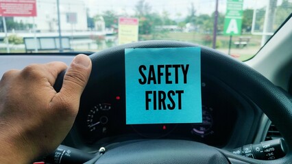 hands holding a car steering wheel and paper with the word SAFETY FIRST. the main concept of safety in driving