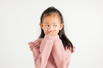 Asian portrait young kid girl standing surprised excited shocked covering mouth with hands for mistake on white background, kindergarten child secret concept with copy space for text