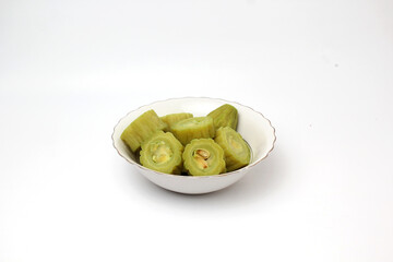 A bowl of sliced bitter melon (pare) on a white background, ready for cooking or serving