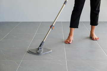 Woman mops the indoor floor, cleaning the front area of her home with a mop and rag. Housewife dedicated to maintaining cleanliness. Represents professional housekeeping and house maintenance concepts