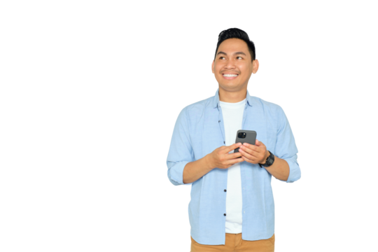 Smiling young Asian man in casual clothes holding smartphone, chatting online and surfing internet, looking aside with happy expression isolated on transparent background