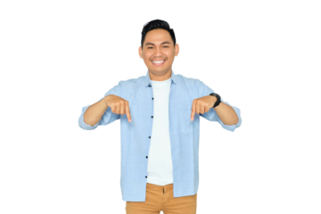 Here and now. Handsome young Asian man in casual clothes pointing finger down, looking at camera with happy expression isolated on transparent background