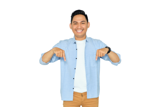 Here and now. Handsome young Asian man in casual clothes pointing finger down, looking at camera with happy expression isolated on transparent background