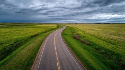 Fototapeta premium Open Road Through Green Fields Under Dramatic Sky