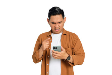 Angry young Asian man in casual shirt pointing with finger at his smartphone isolated on...