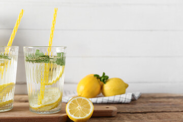 Glasses of fresh lemonade with mint and lemons on wooden table