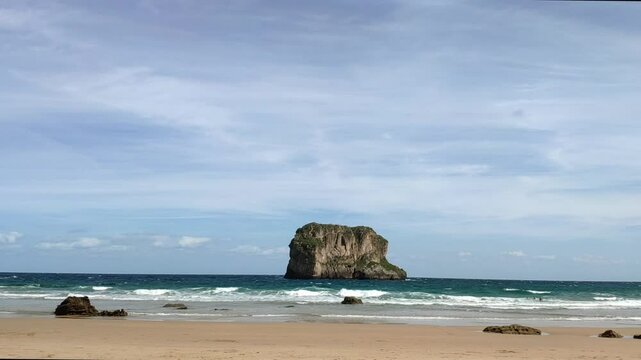 Beach view of Castro Ballota Islet from Ballota Beach in Asturias, showcasing the coastline and clear skies