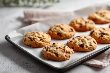 Baking tray with cookies on parchment paper on white table