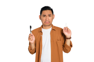 Confused young Asian man in casual shirt holding toothbrush and cigarette isolated on transparent background
