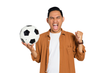 Excited young Asian man in casual shirt holding soccer ball, screaming with mouth wide open, celebrating victory isolated on transparent background