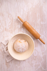 Raw yeast dough with rolling pin resting and rising in a special basket
