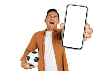 Excited young Asian man in casual shirt holding soccer ball and smartphone with blank screen, celebrating his victory isolated on transparent background