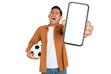 Excited young Asian man in casual shirt holding soccer ball and smartphone with blank screen, celebrating his victory isolated on transparent background