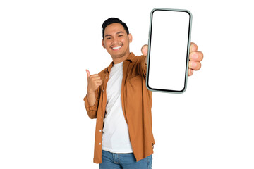 Happy young Asian man in casual shirt showing smartphone with blank screen and thumb up isolated on...