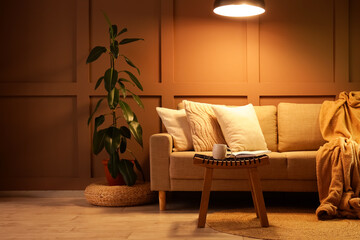 Interior of stylish living room with cozy sofa, coffee table and glowing lamps at evening